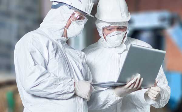 cropped photo of hazmat workers with computer